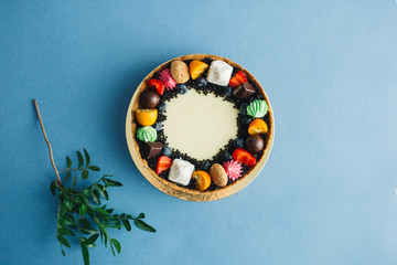 Sweet cake with berries and flowers, on a blue background with ribbons and draperies