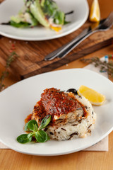 Close up of a steamed fish in tomato gravy with wild boiled rice and sunflower sprouts for diet dinner in a cafe, served  on a wooden table and white dish