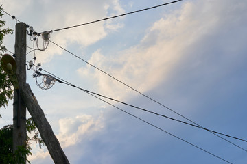 Old wooden electric street post with wires on sky background.