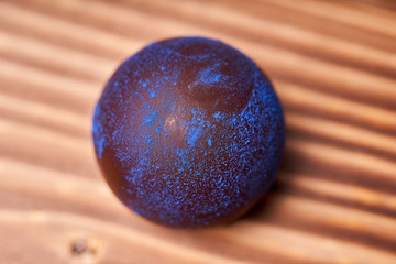 Chocolates with blue algae on wooden background.