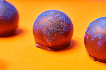 Chocolates with blue algae on colored background.