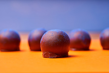 Chocolates with blue algae on colored background.