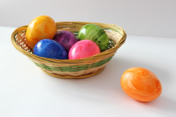 Bunte Ostereier in einem Korb vor weißem Hintergrund 