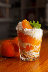 Seasonal tangerine dessert with whipped cream cheese, decorated with fresh mint and placed on a bar counter