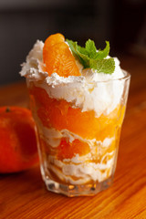 Seasonal tangerine dessert with whipped cream cheese, decorated with fresh mint and placed on a bar counter