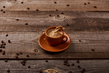 coffee splash in cup on wooden table with scattered coffee beans