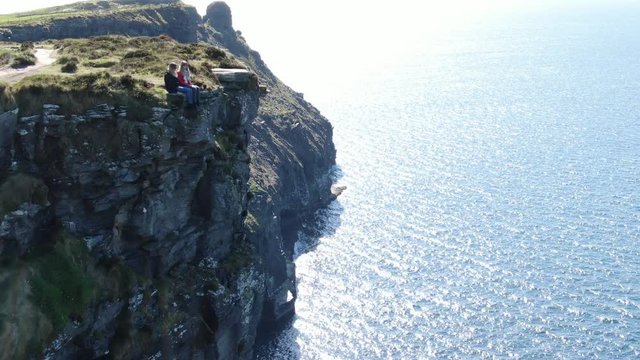 Two girls sit on the edge of the famous Cliffs of Moher in Ireland - travel photography