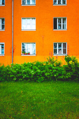 Fototapeta na wymiar orange apartment building with green bush in the foreground