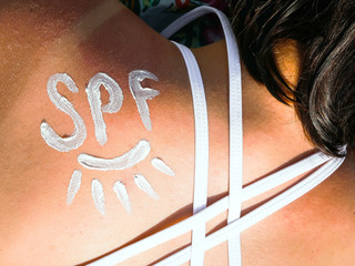 SPF shaped cream on the shoulder of young girl like a sign of protect from the sun. The reminder of the importance of using creams with SPF protection. Summer Travel Vacation Concept