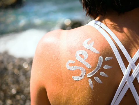 SPF shaped cream on the shoulder of young girl like a sign of protect from the sun. The reminder of the importance of using creams with SPF protection. Summer Travel Vacation Concept