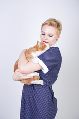 cute kind woman with short hair in pinup polka dot dress holding her beloved pet on a white background in the Studio. plus size adult blonde girl and her orange cat are happy together.