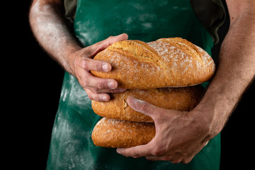 Freshly baked tasty bread in the baker's hands. Tasty baked goods straight from the bakery.