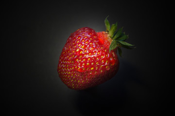 Fresh strawberries in a bowl on wooden table with low key scene.