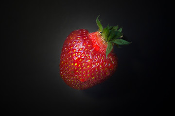 Fresh strawberries in a bowl on wooden table with low key scene.