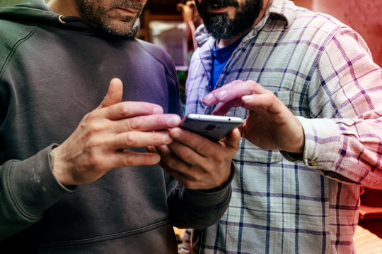two men in casual wear focusing on the mobile phone