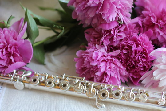 silver flute with a bouquet of pink peonies, color photography
