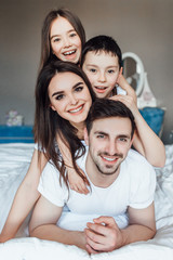 Photo of young family of four lying on nice white bed. Family weekend.. Resting and relax..