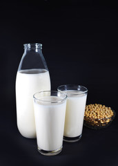 Botella, vasos de leche de soja y bol con granos de soja 