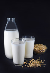 Botella y vasos de leche de soja, bol con granos de soja 