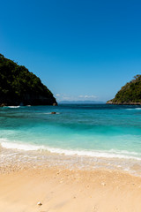 View of tropical beach, sea rocks and turquoise ocean, blue sky. Atuh Beach, Nusa Penida, Indonesia.