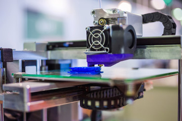 3D printer prints physical 3D model with plastic wire filament at modern technology exhibition. Additive technologies, science and futuristic concept