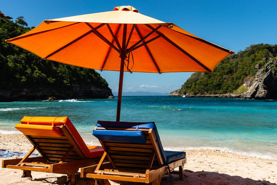 Pair Of Sun Loungers And A Beach Umbrella On A Deserted Beach. Perfect Vacation Concept