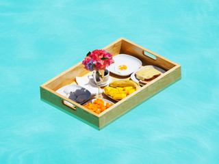 top view of breakfast in swimming pool on a floating table outside in a hotel.