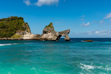 View of tropical beach, sea rocks and turquoise ocean, blue sky. Atuh Beach, Nusa Penida, Indonesia.