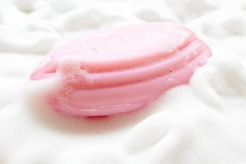 Pink soap on foam bubbles background.