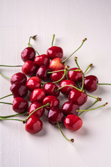 Cherry berries with stem on wooden white background and water drops