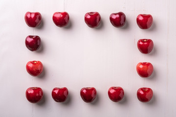 Cherry berries frame pattern macro texture on wooden white background and water drops top view