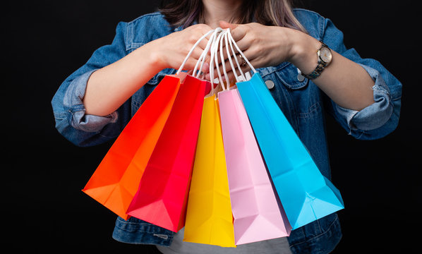 Close up photo of woman holding many colorful shopping bags