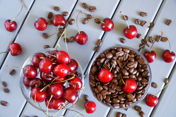 Roasted coffee grains next to red cherries on a light background. Fruit flavor favorite drink