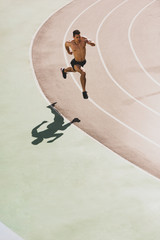 Shirtless athlete running on track