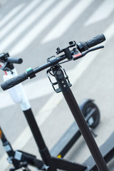Fototapeta premium Modern сity transport - Three electric scooters are parked on the street of the city.