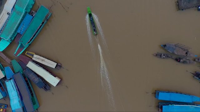 Aerial view of a motor boat passing by the Mekong river on the country side of Cambodia. A group of boats parked on the river.