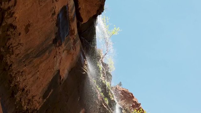 Slow motion: Zion national park Emerald pool fall flows over the rock edge, followed.