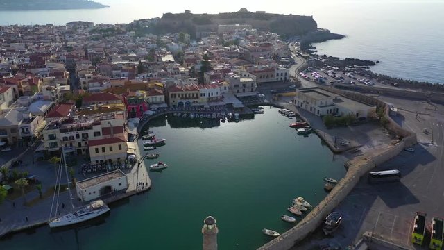 Aerial drone video of unique old picturesque Venetian port with old lighthouse in the heart of famous city of Rethymno at sunset, Crete island, Greec