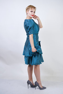 a beautiful girl with a plus size figure dressed in a cute retro fashion dress and stands on a white background. young short hair chubby woman posing in the studio.