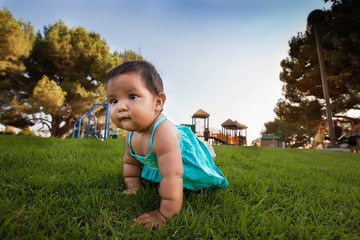 A curious little baby girl crawls away from a kids playground to explore, and is unsupervised by...