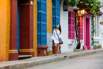 Beautiful woman on white dress walking alone at the colorful streets of the colonial walled city of...