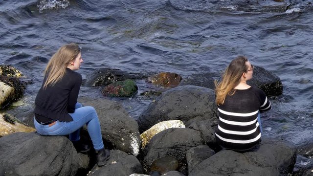 Two girls sit on the rocks at the Causeway Coast in Northern Ireland - travel photography