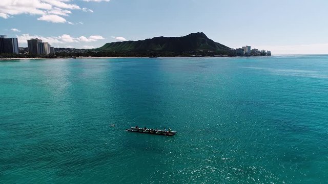 Flying over rowers in clear blue water, with Diamond Head in the background.
