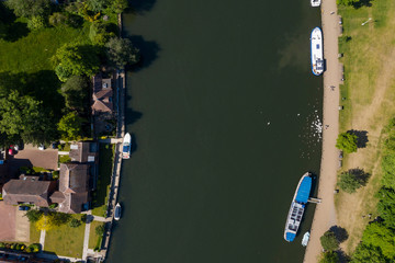 Overhead view of swans being fed next to some moored boats and houses on the river Thames in Marlow, Buckinghamshire, UK