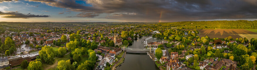 Fototapeta na wymiar Dramatic aerial panoramic view of the beautiful town of Marlow in Buckinghamshire UK, captured after a rain storm, with a rainbow on the horizon