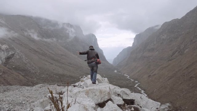 Man jumps on the rocks of a panoramic view on Huascaran Natural Park to escape of the storm. Slow motion