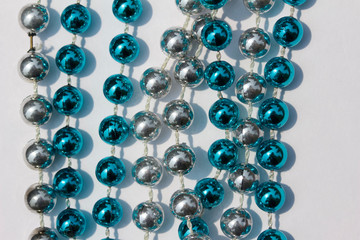 Abstract design of blue and silver metallic Mardi Gras beads on white background