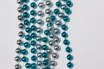 Abstract design of blue and silver metallic Mardi Gras beads on white background