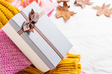 Fototapeta premium Beautiful gift box with a knitted sweater and a rose on a white fabric background 