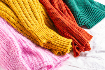 Colorful knitted sweaters on white background 
